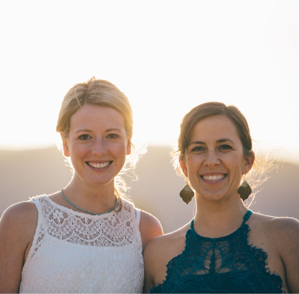 Cara and Amber standing shoulder to shoulder outside with the sun setting behind them